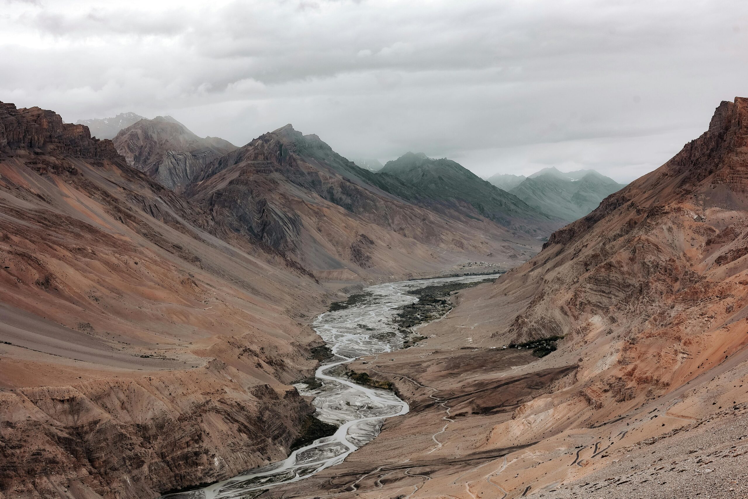 Explore the stunning landscape of Spiti Valley, featuring breathtaking mountains and rivers under cloudy skies.