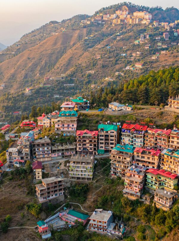Aerial view of colorful houses on a Shimla hillside at sunrise, Himachal Pradesh.