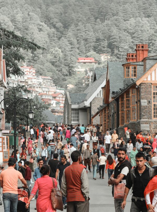 Lively crowd on a street in Shimla, India, surrounded by historic architecture and scenic hills.